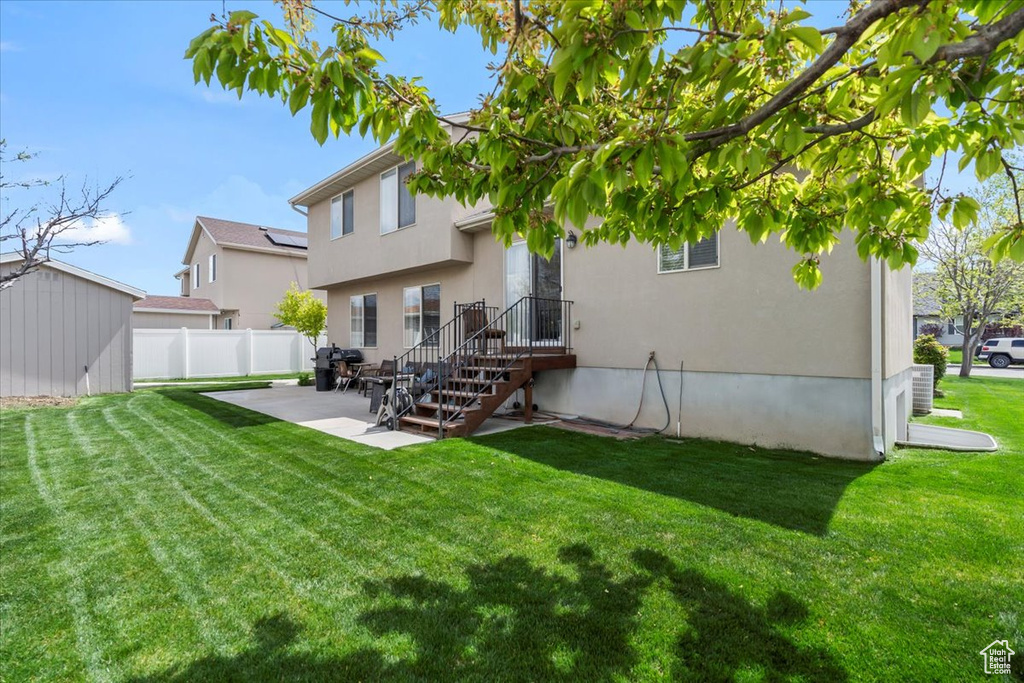 Rear view of property with an outdoor structure, fence, a shed, a patio area, and a yard