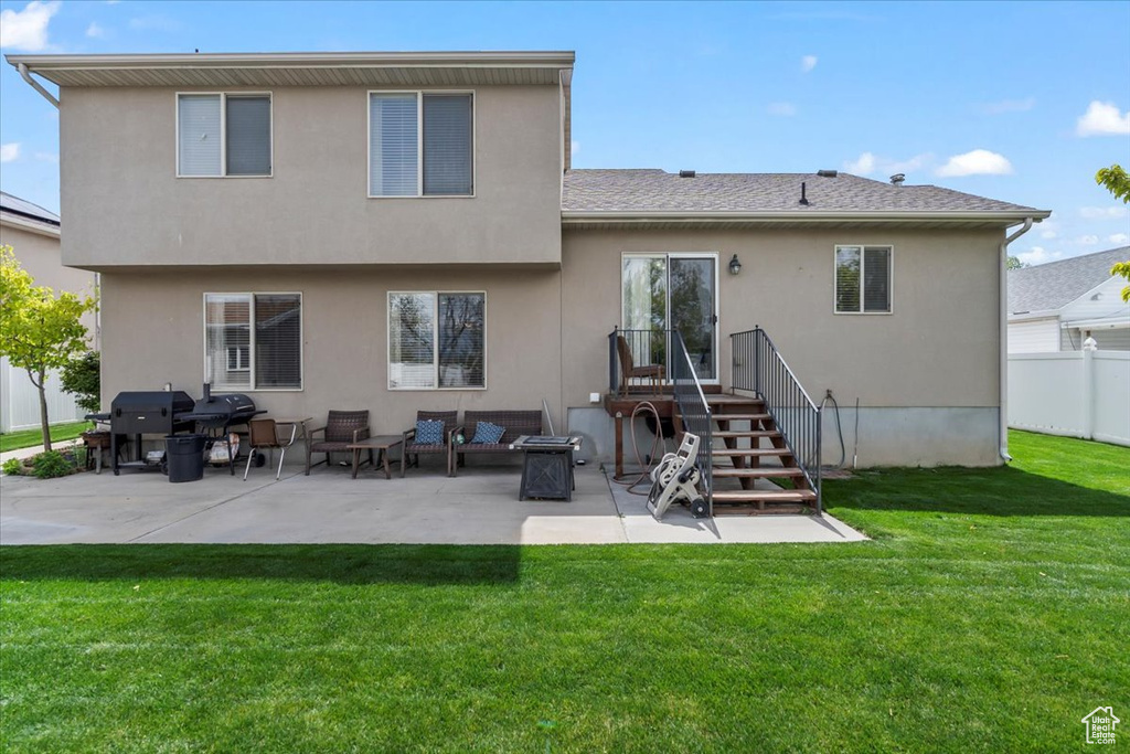 Rear view of property with a lawn, fence, stucco siding, and a patio area