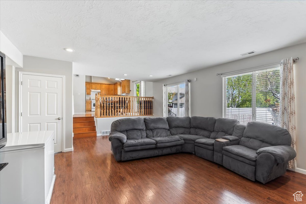 Living room with visible vents, dark wood-style flooring, stairs, recessed lighting, and a textured ceiling