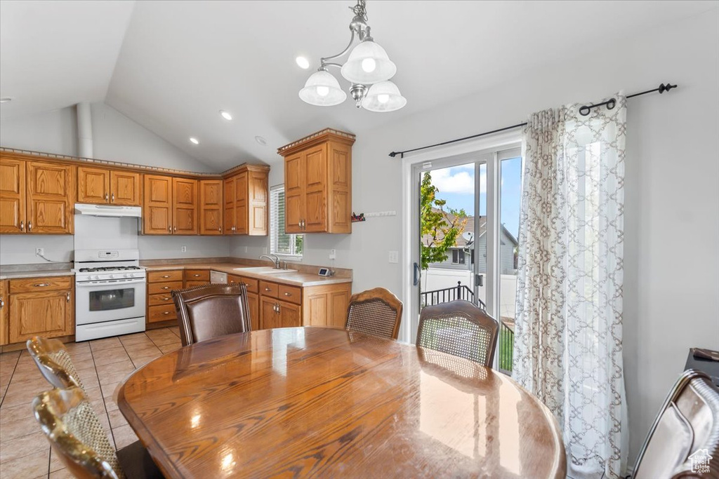 Kitchen featuring under cabinet range hood, white gas range oven, vaulted ceiling, and light countertops