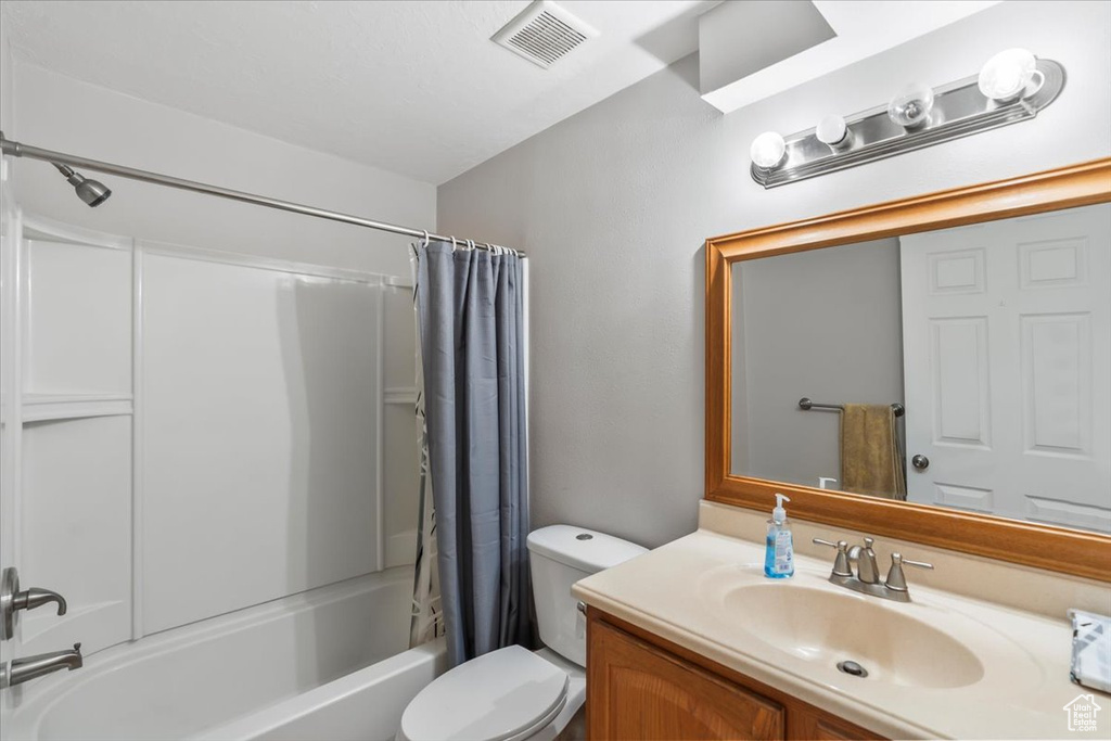 Full bathroom featuring shower / tub combo, vanity, toilet, and visible vents