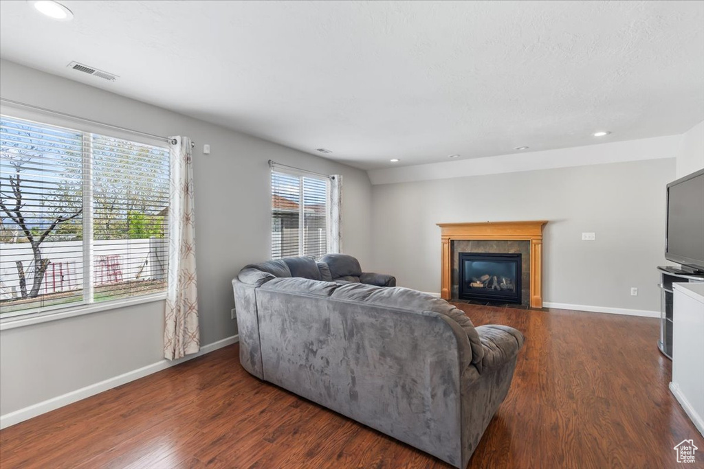 Living room featuring a fireplace with flush hearth, recessed lighting, and dark wood-style floors
