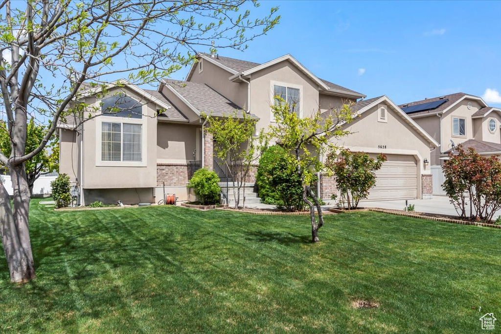 View of front of property with a garage, stucco siding, concrete driveway, and a front lawn