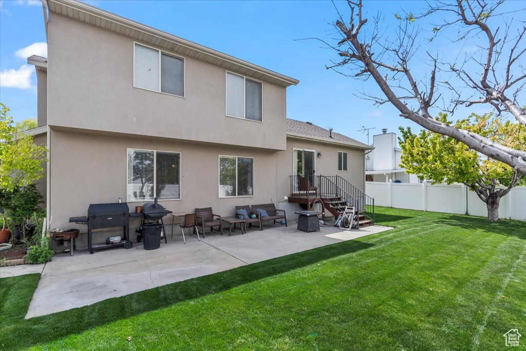 Back of house featuring a lawn, a patio, fence, and stucco siding