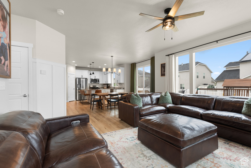 Living area featuring recessed lighting, light wood finished floors, and ceiling fan with notable chandelier
