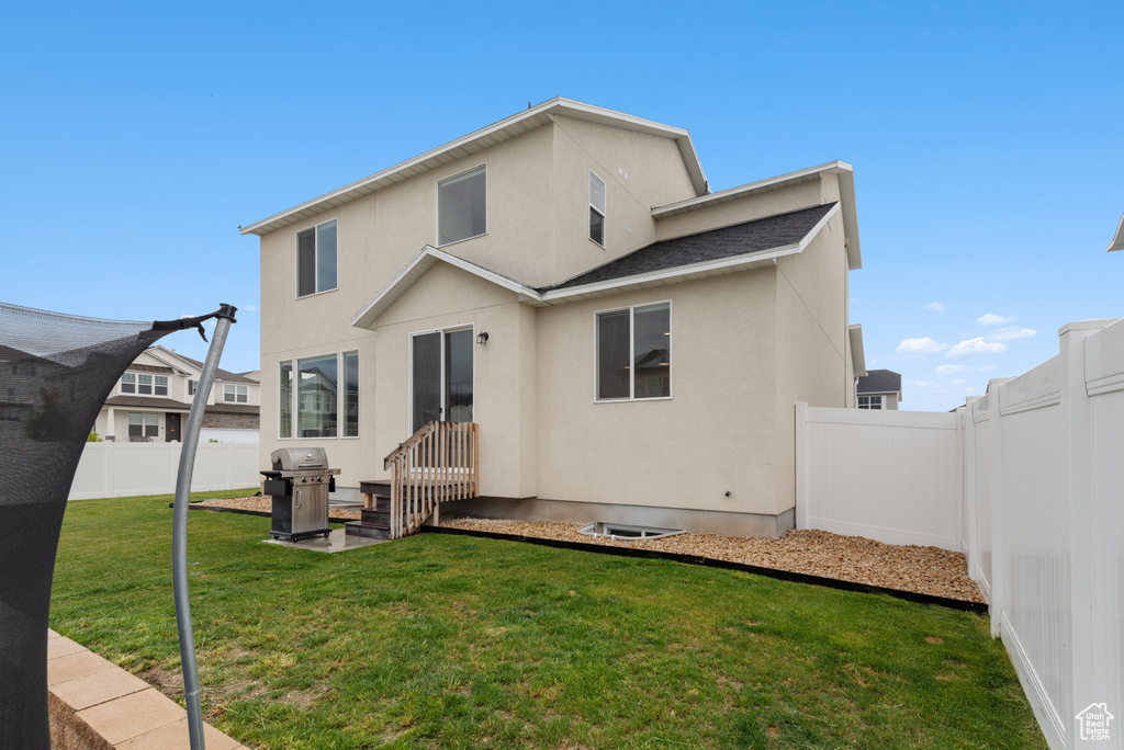 Rear view of house with a lawn, a fenced backyard, and stucco siding