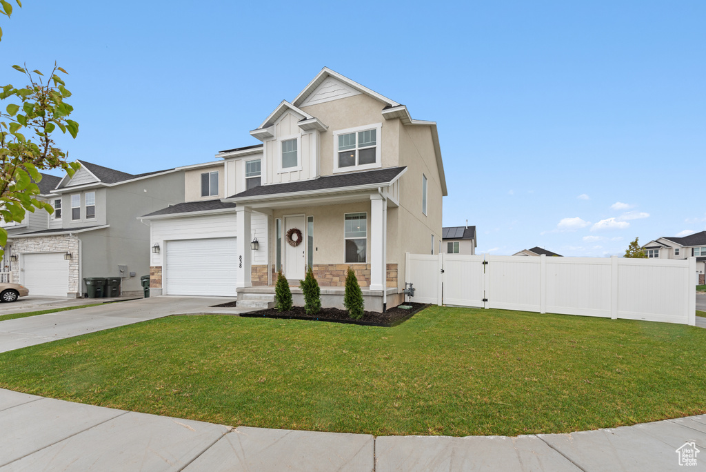 View of front facade with fence, a garage, a front yard, a gate, and driveway