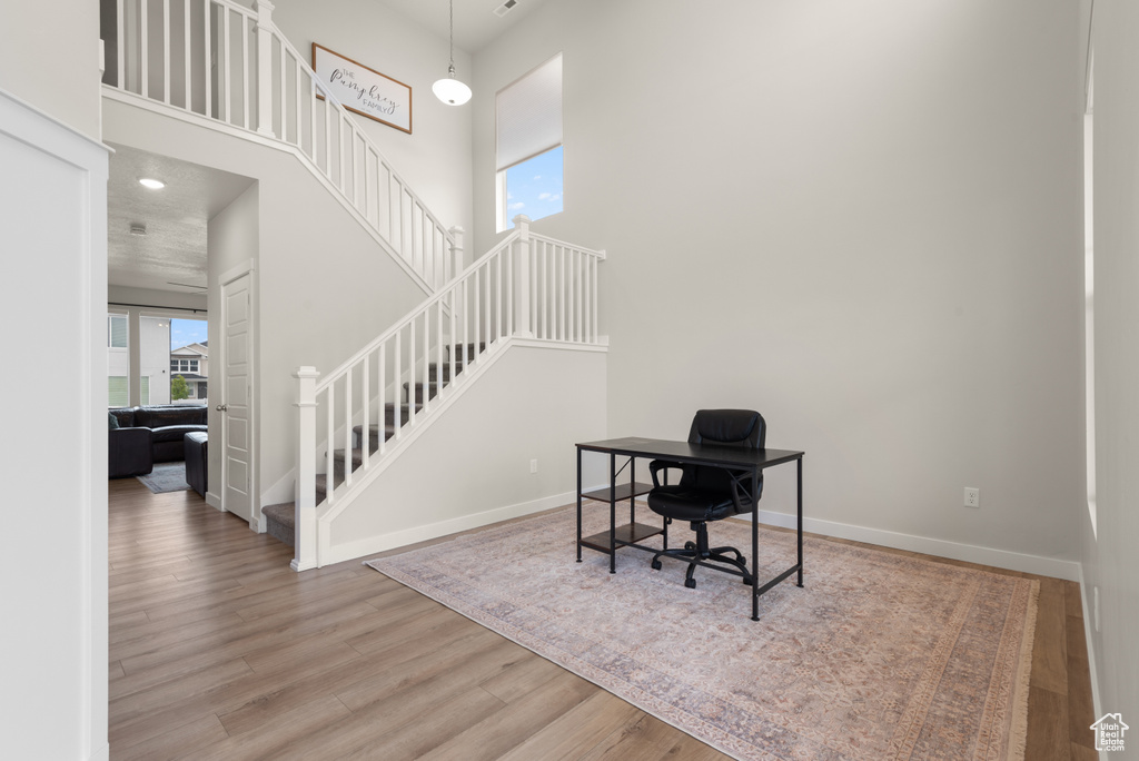 Home office featuring baseboards, a high ceiling, and wood finished floors