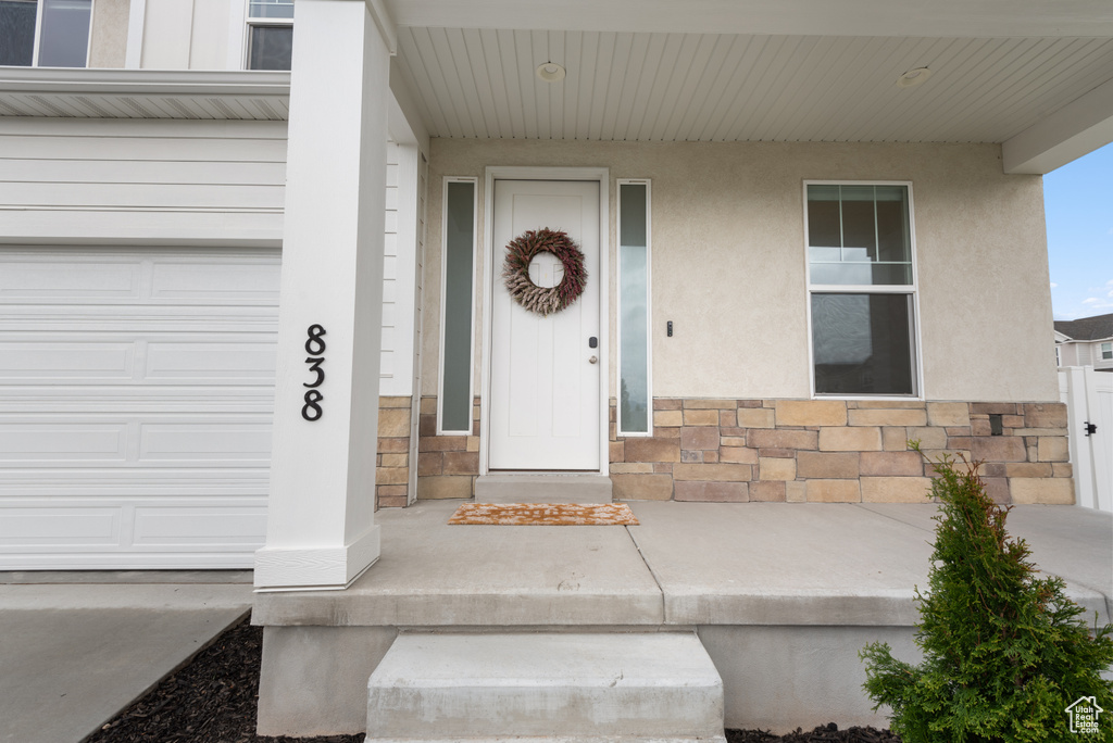 Property entrance with a garage, stucco siding, and stone siding