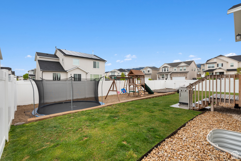 View of yard featuring a fenced backyard, a trampoline, a playground, and a residential view