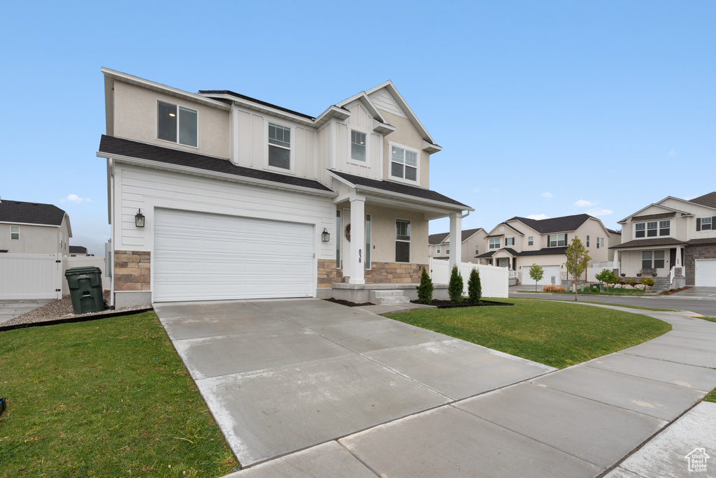 Craftsman-style house with a garage, a front yard, stone siding, driveway, and a residential view