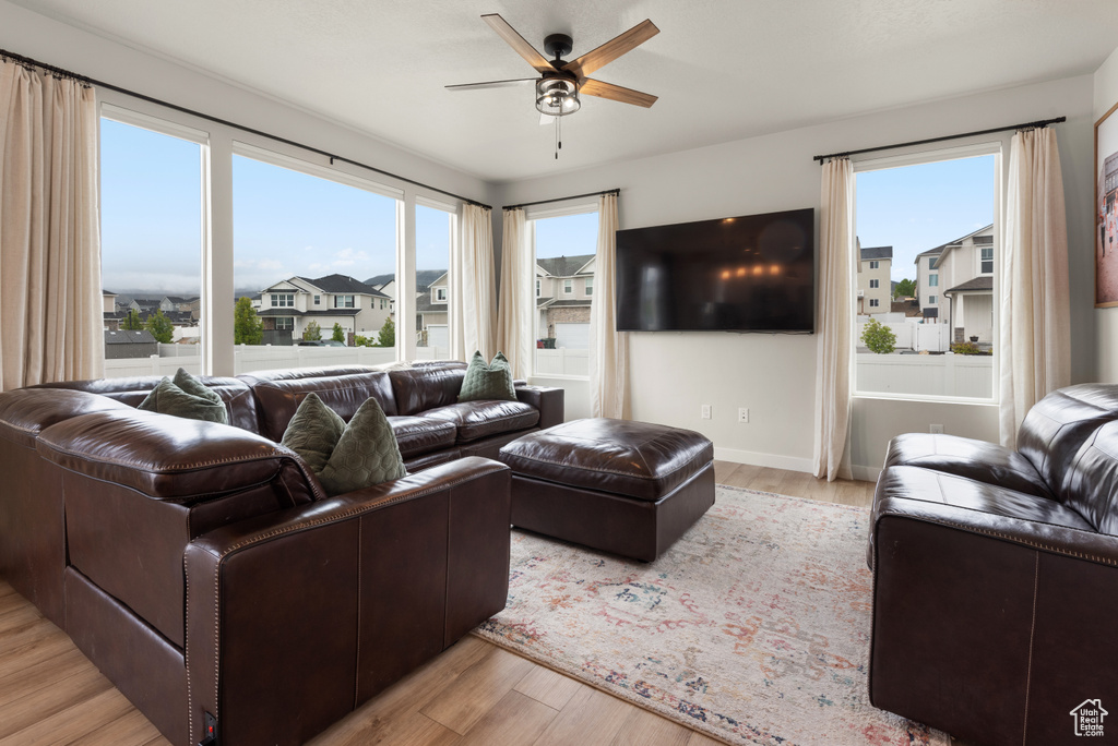 Living area featuring baseboards, a residential view, a ceiling fan, and light wood finished floors