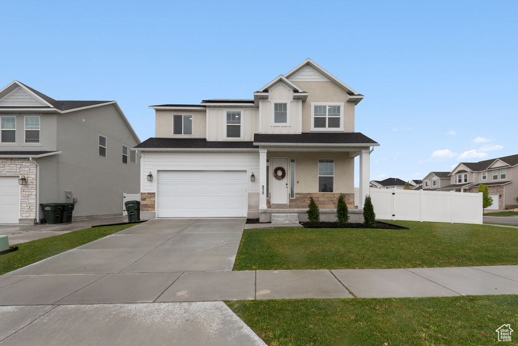 View of front of property with fence, an attached garage, a front lawn, a porch, and driveway