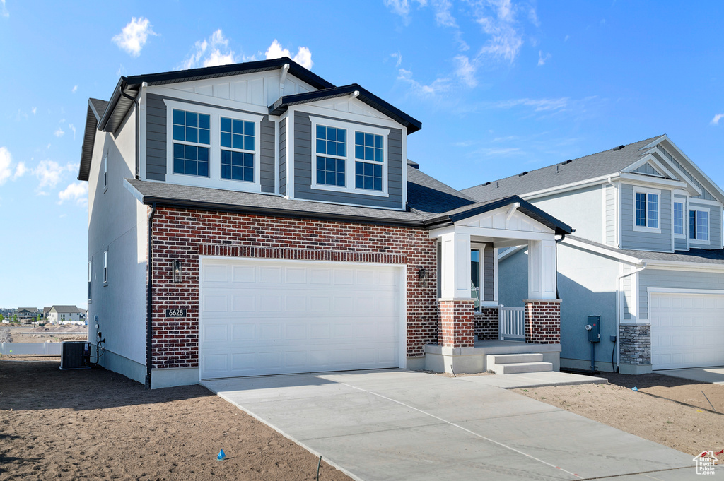 View of front of home with covered porch, a garage, driveway, and brick siding