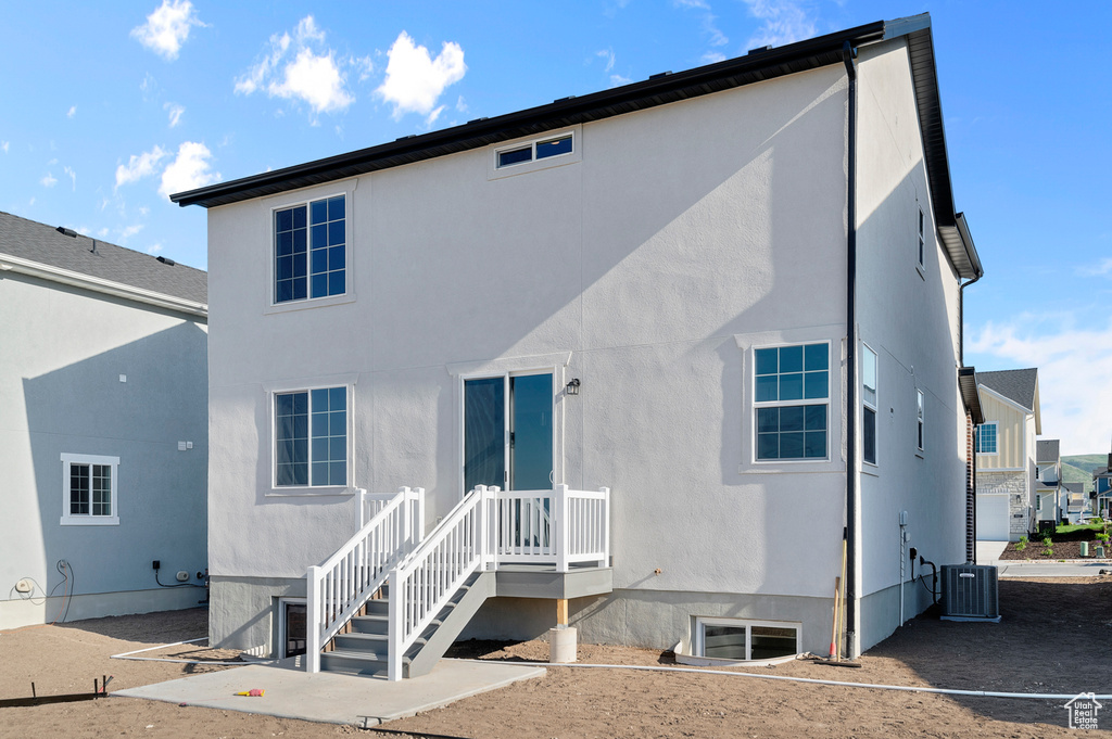 Back of property with stucco siding and central air condition unit