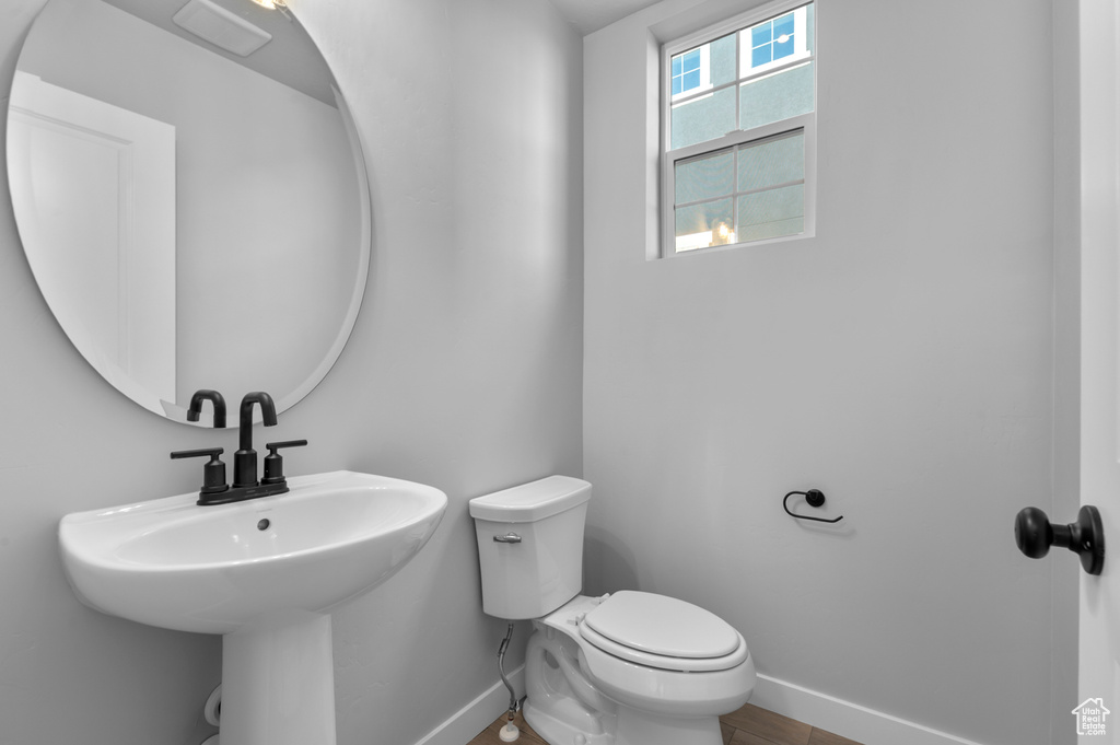 Half bathroom featuring baseboards, toilet, and a sink
