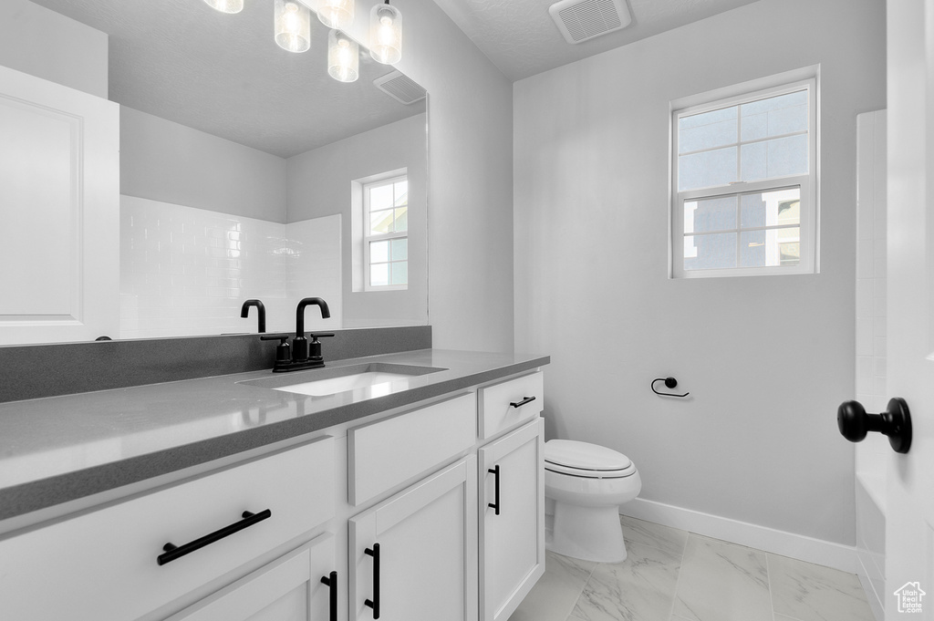 Full bathroom featuring vanity, toilet, marble finish floors, and baseboards