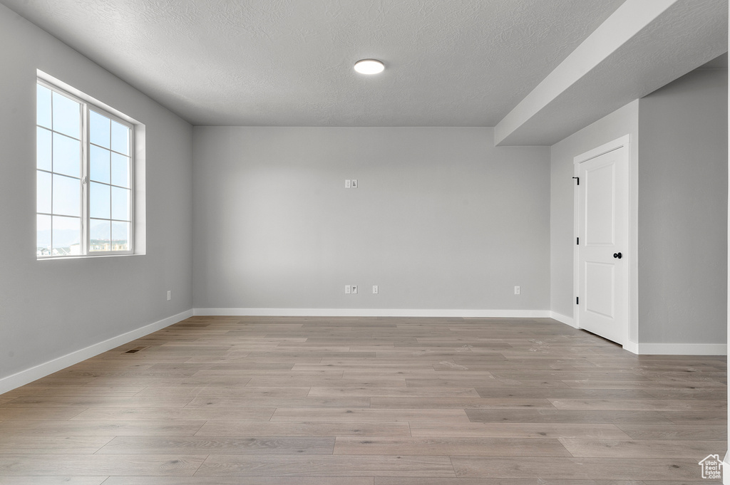 Unfurnished room with a textured ceiling, baseboards, and light wood-style flooring