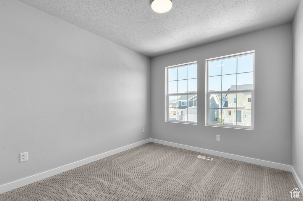 Carpeted spare room featuring baseboards and a textured ceiling