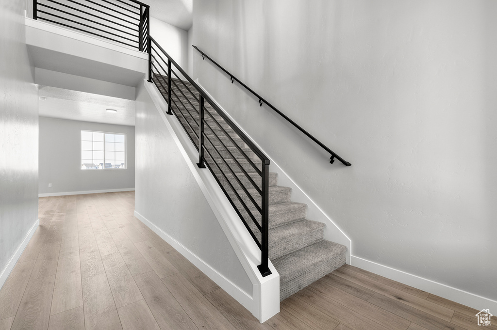 Stairway with wood finished floors and baseboards