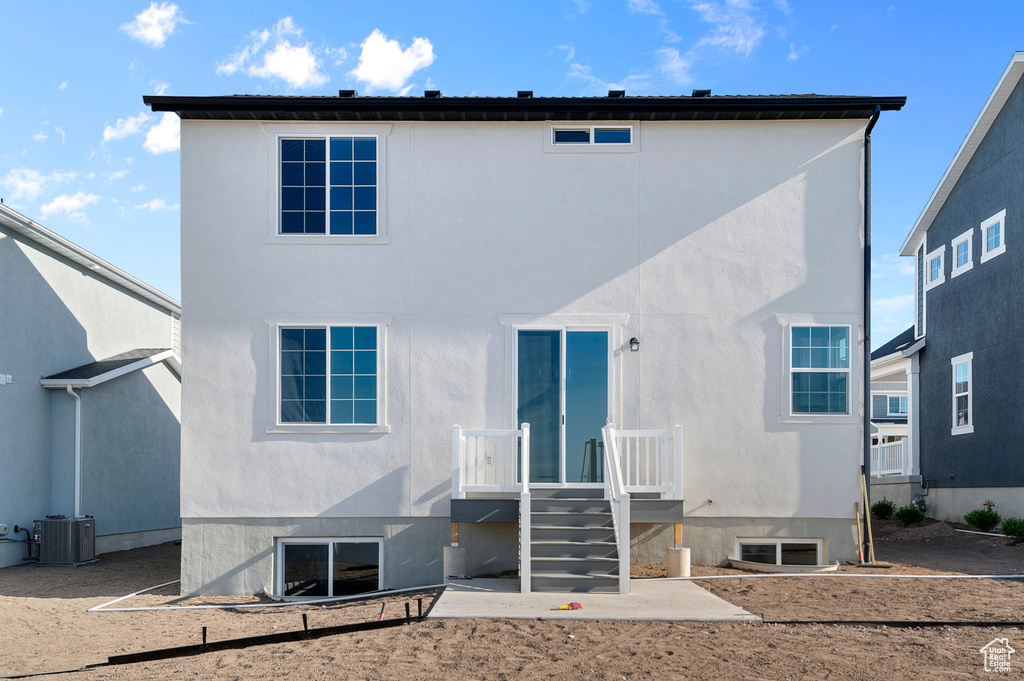 Back of house with central AC unit and stucco siding