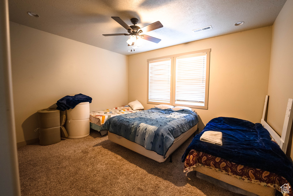 Bedroom featuring a ceiling fan, carpet flooring, and visible vents