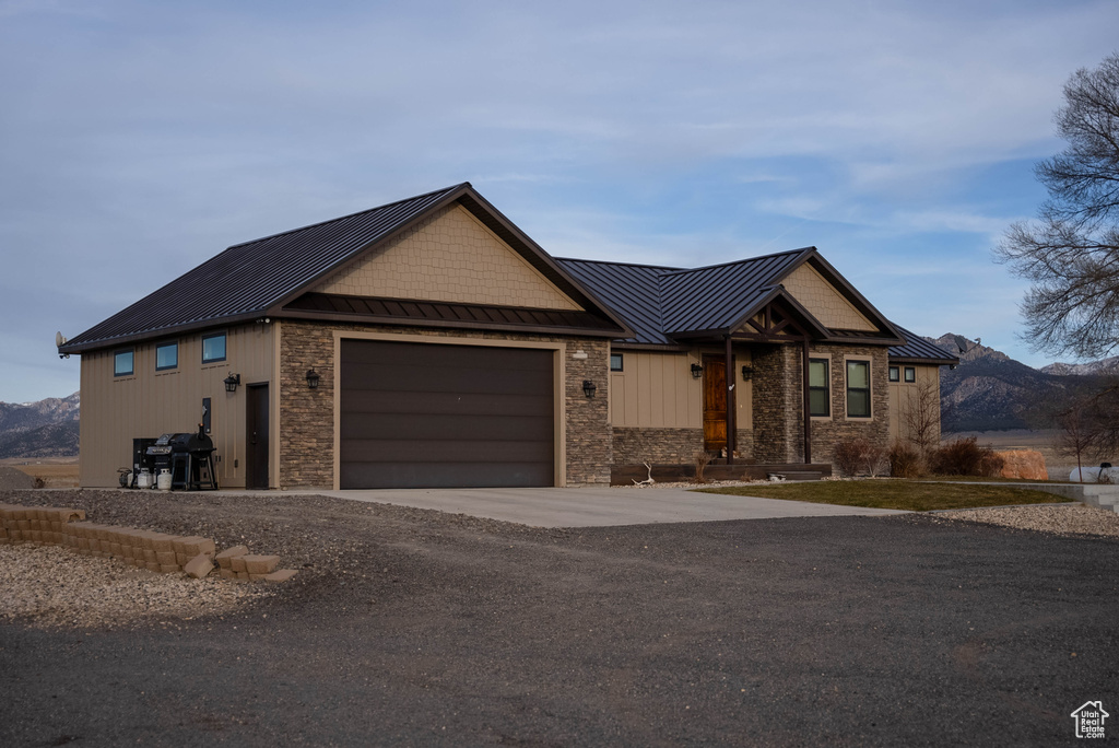 View of front of home featuring a standing seam roof, metal roof, concrete driveway, an attached garage, and stone siding