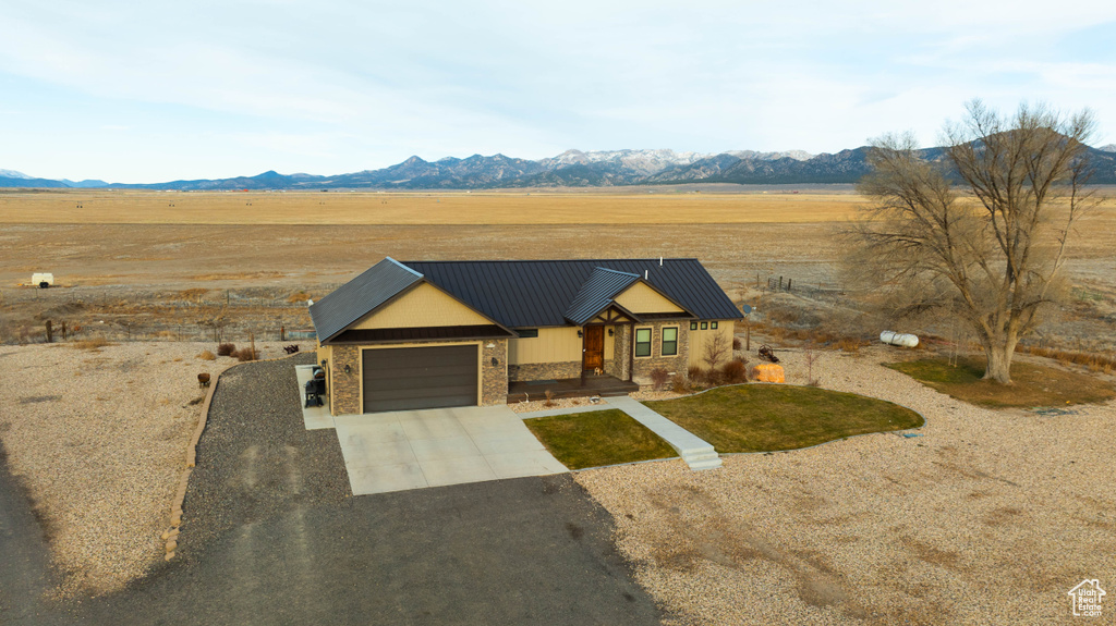View of front of property featuring driveway, metal roof, a mountain view, a rural view, and an attached garage