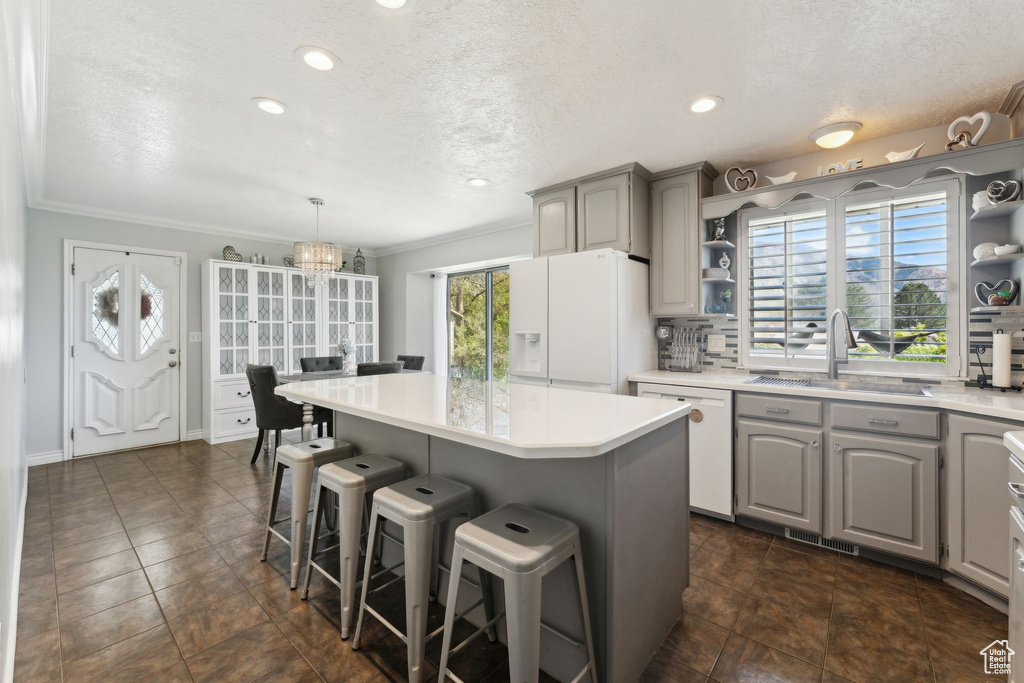 Kitchen with a kitchen island, open shelves, a sink, gray cabinetry, and white appliances
