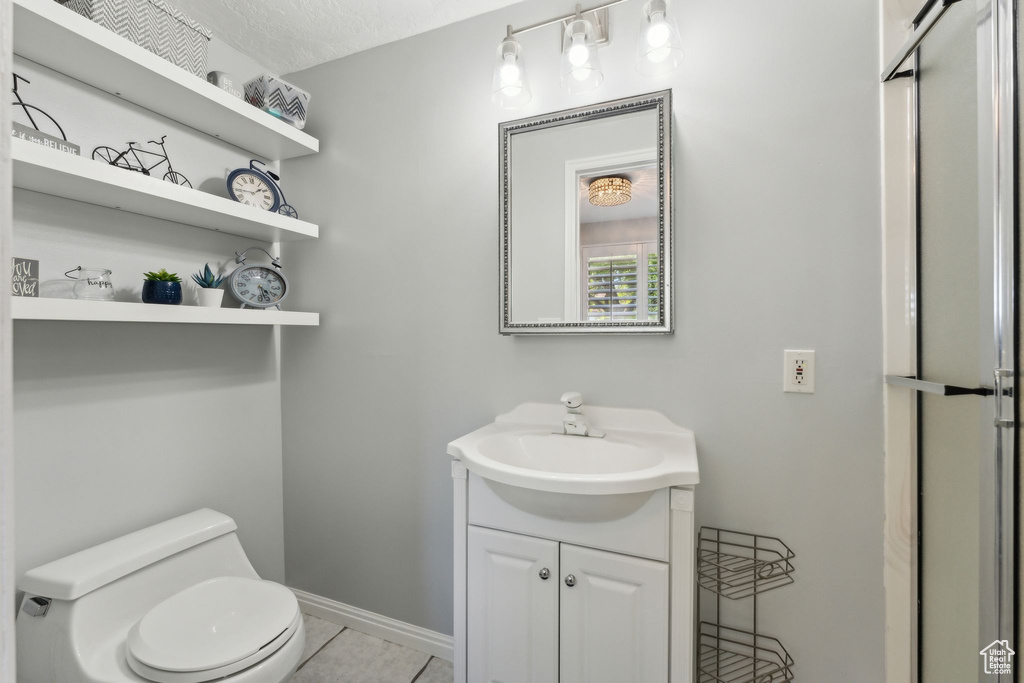 Bathroom featuring vanity, baseboards, tile patterned flooring, and toilet