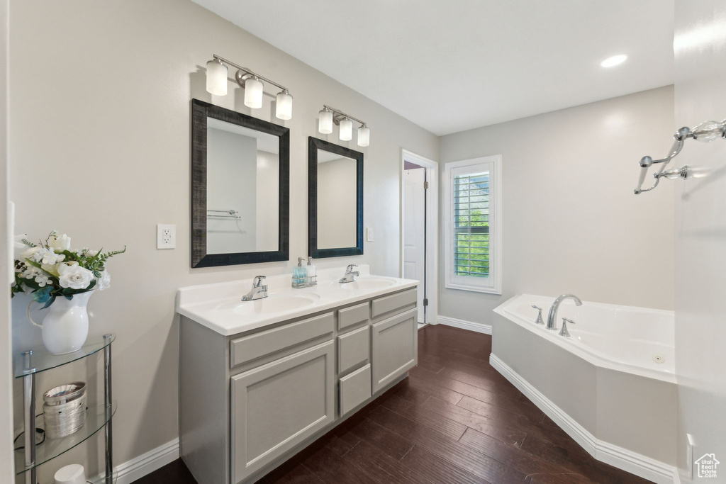 Full bathroom featuring a sink, baseboards, a bath, and hardwood / wood-style floors