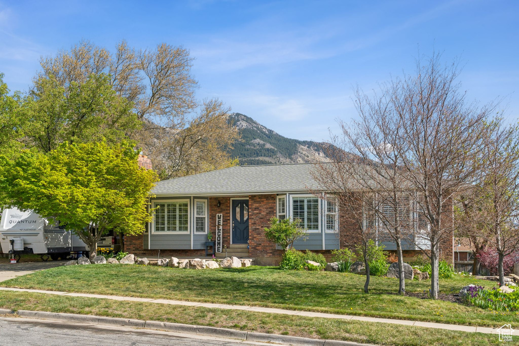 Ranch-style house featuring brick siding, a front lawn, and a mountain view