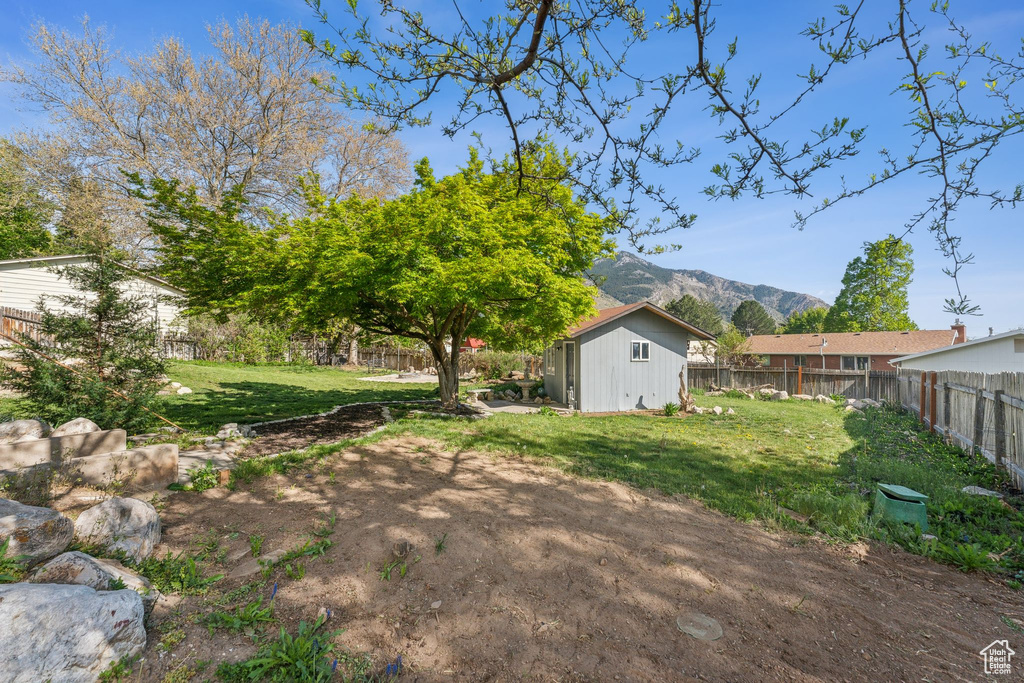 View of yard with a mountain view, an outbuilding, a fenced backyard, and a storage unit