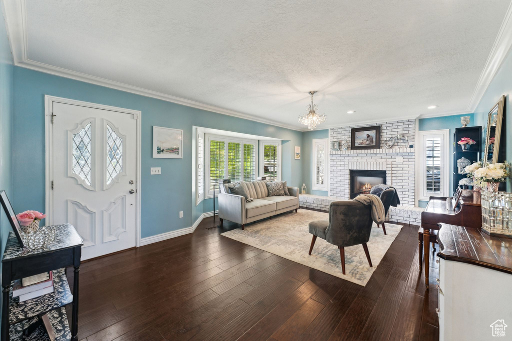 Living area featuring an inviting chandelier, crown molding, hardwood / wood-style floors, baseboards, and a textured ceiling