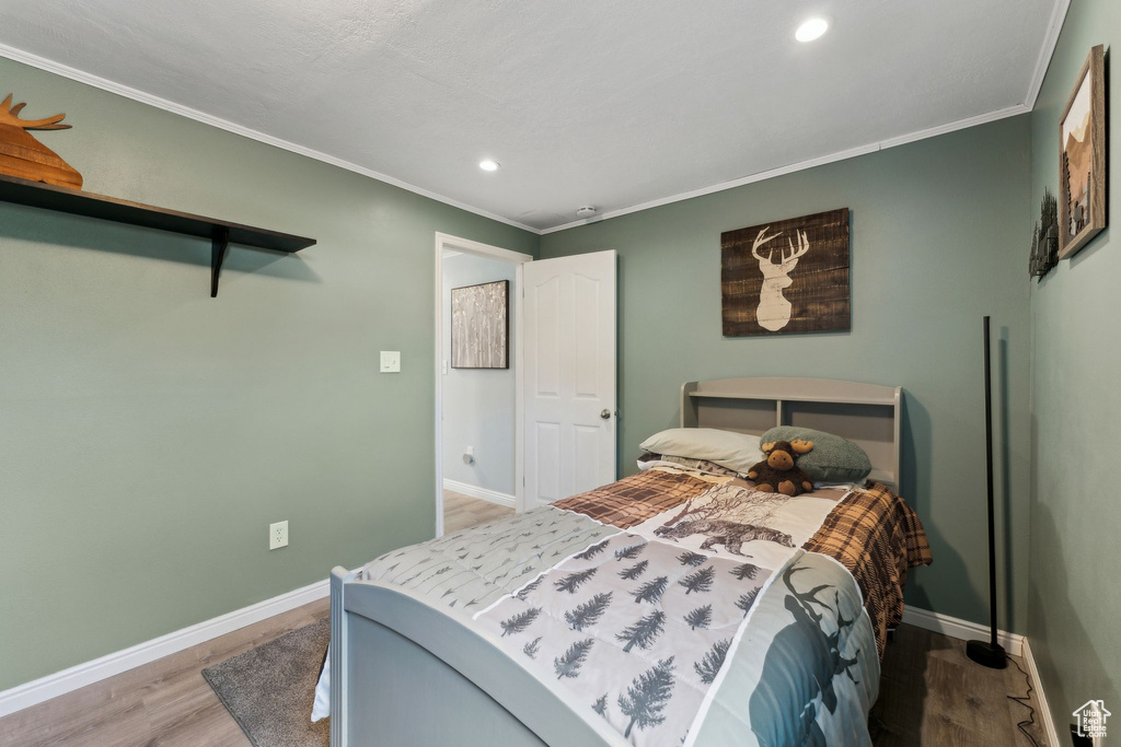 Bedroom featuring crown molding, baseboards, and wood finished floors