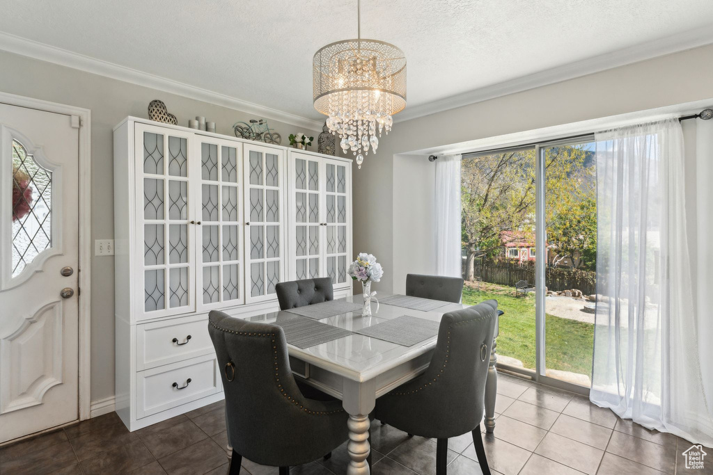 Tiled dining space with crown molding and a chandelier