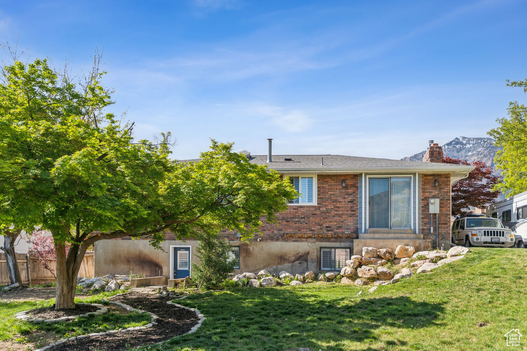 Rear view of house with a yard, brick siding, fence, and a chimney