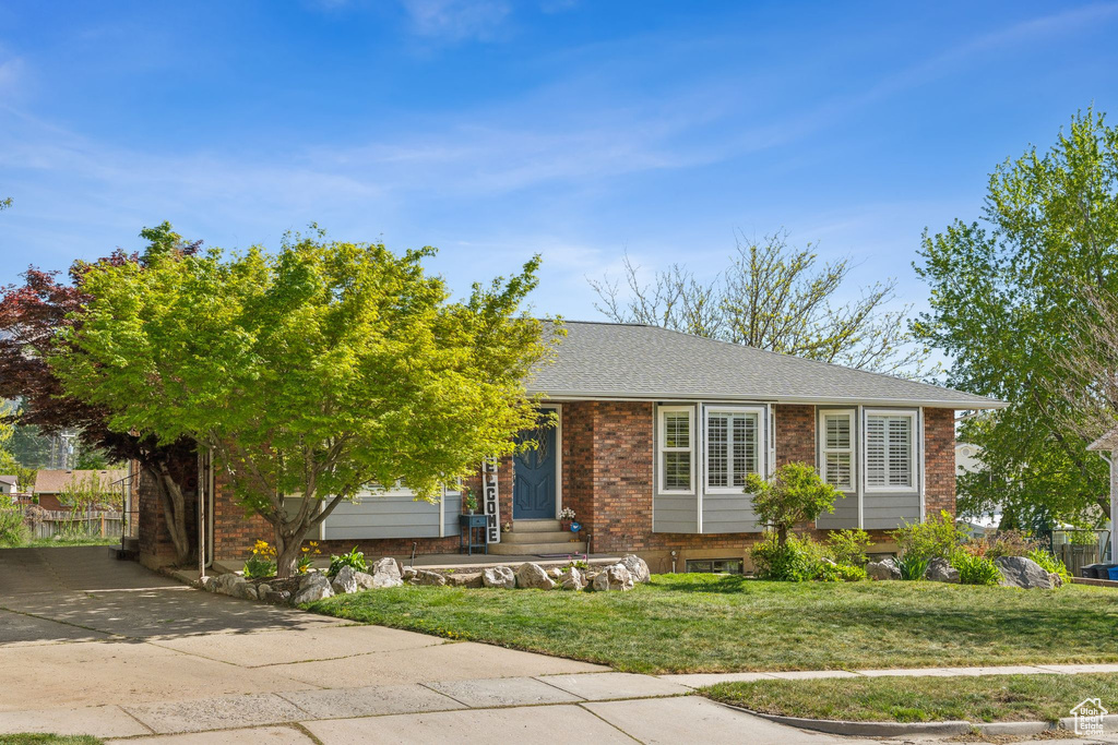 View of front of property featuring concrete driveway, brick siding, a front yard, and entry steps