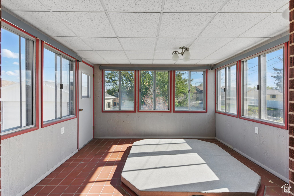 Unfurnished sunroom featuring baseboards, a drop ceiling, and tile patterned floors