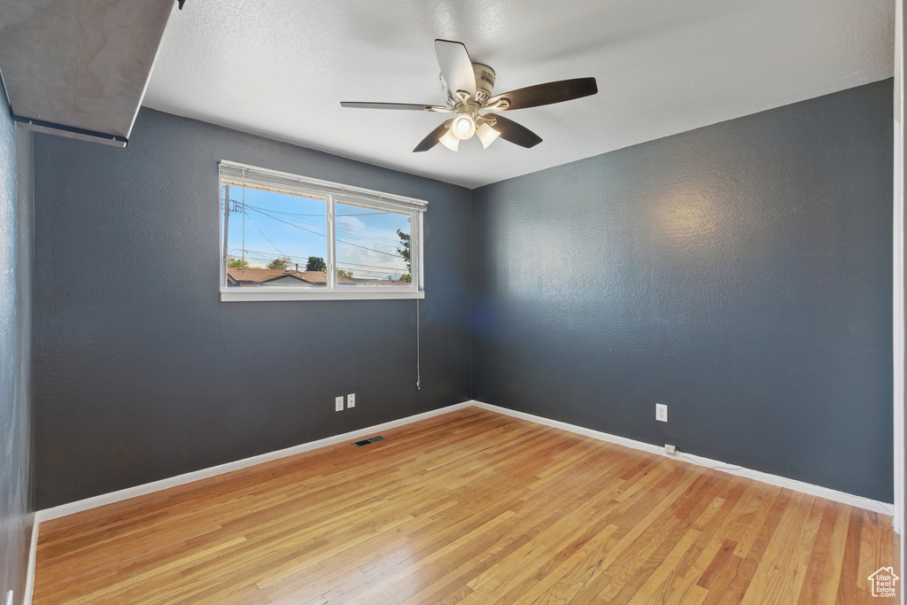 Unfurnished room featuring light wood-style floors, baseboards, a ceiling fan, and visible vents