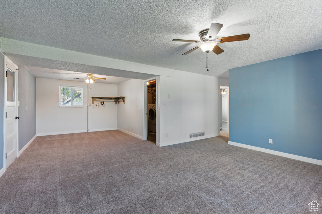 Carpeted empty room featuring visible vents, a textured ceiling, ceiling fan, and baseboards