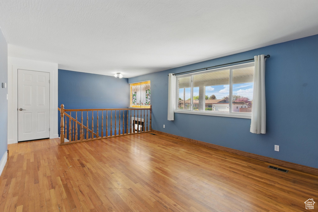 Unfurnished room featuring baseboards, visible vents, and wood finished floors