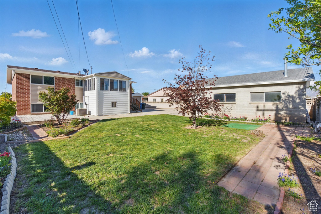Back of house with a yard, brick siding, and stairs