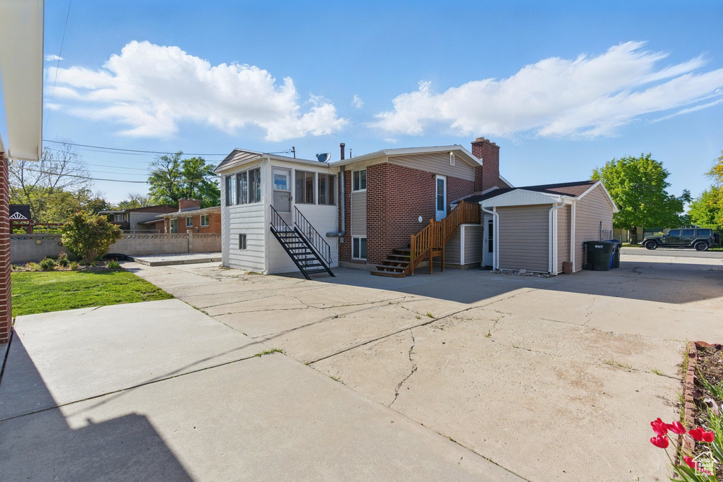 Ranch-style home with fence, a storage unit, stairs, a sunroom, and an outbuilding