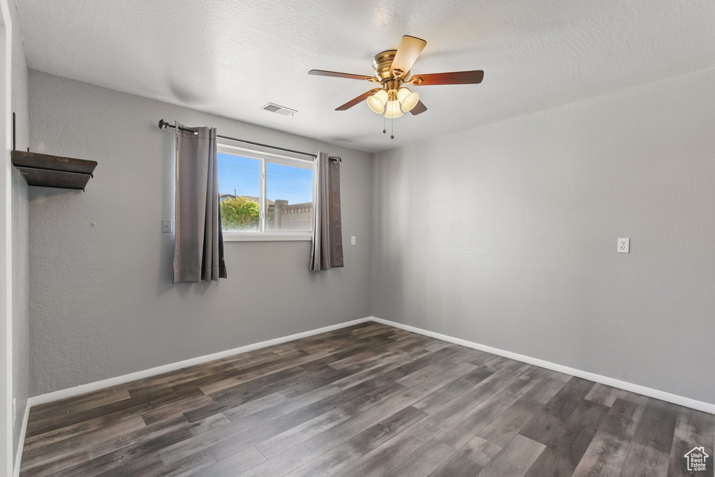Spare room featuring visible vents, a ceiling fan, baseboards, and wood finished floors