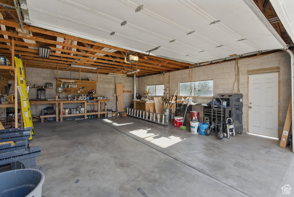 Garage featuring concrete block wall, a workshop area, and a garage door opener