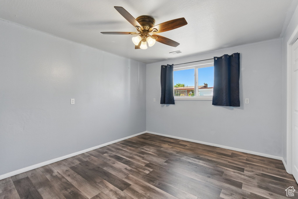 Empty room featuring baseboards, a ceiling fan, dark wood finished floors, and visible vents