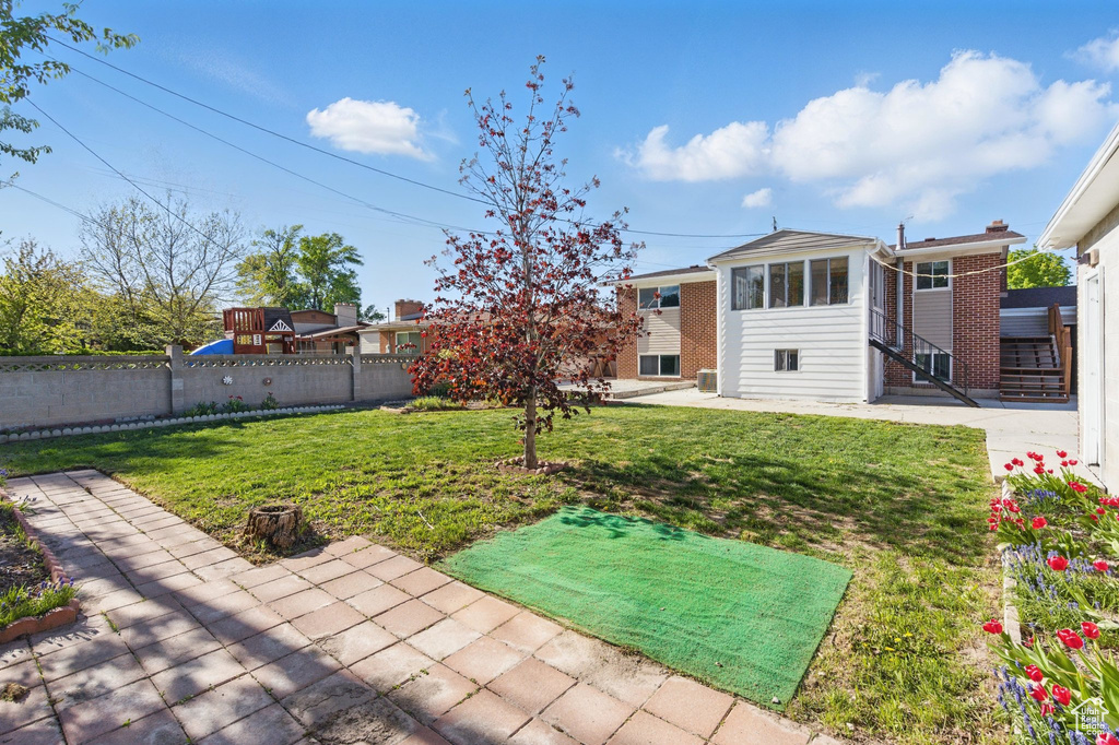 View of yard with fence, a sunroom, and a patio area