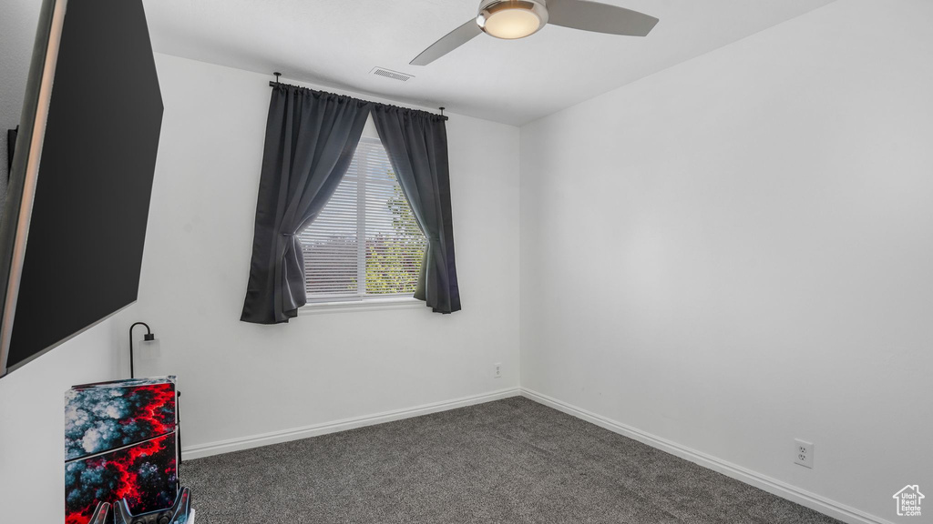 Carpeted spare room featuring baseboards, a ceiling fan, and visible vents