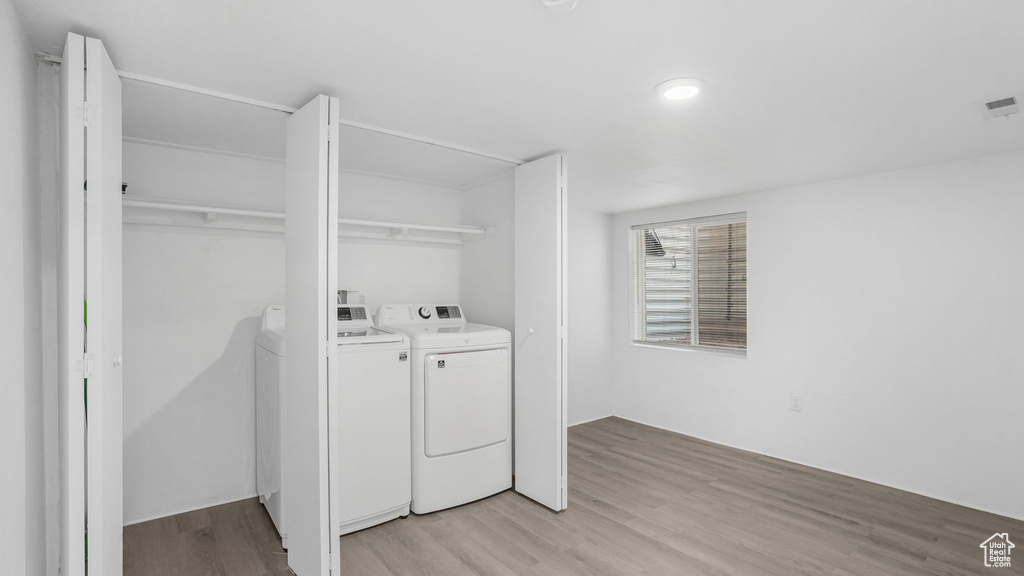 Clothes washing area with washing machine and clothes dryer, laundry area, and light wood-style floors